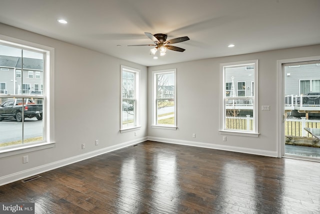 spare room featuring dark hardwood / wood-style flooring, ceiling fan, and a healthy amount of sunlight