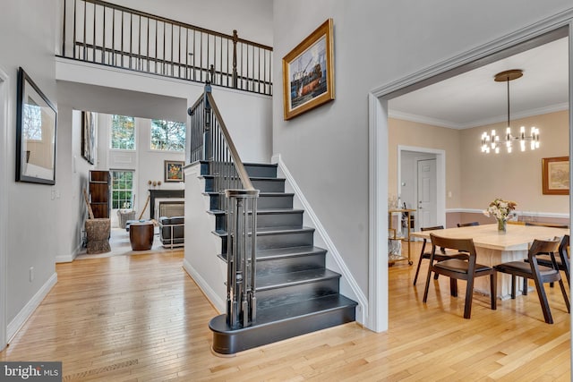 216 Pelagic Ln, Solomons, MD 20688 - stairs featuring hardwood / wood-style flooring, a chandelier, a high ceiling, a fireplace, and baseboards