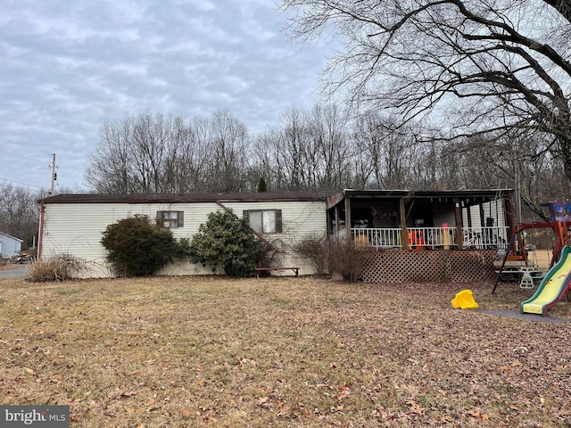 back of house featuring a lawn and a playground