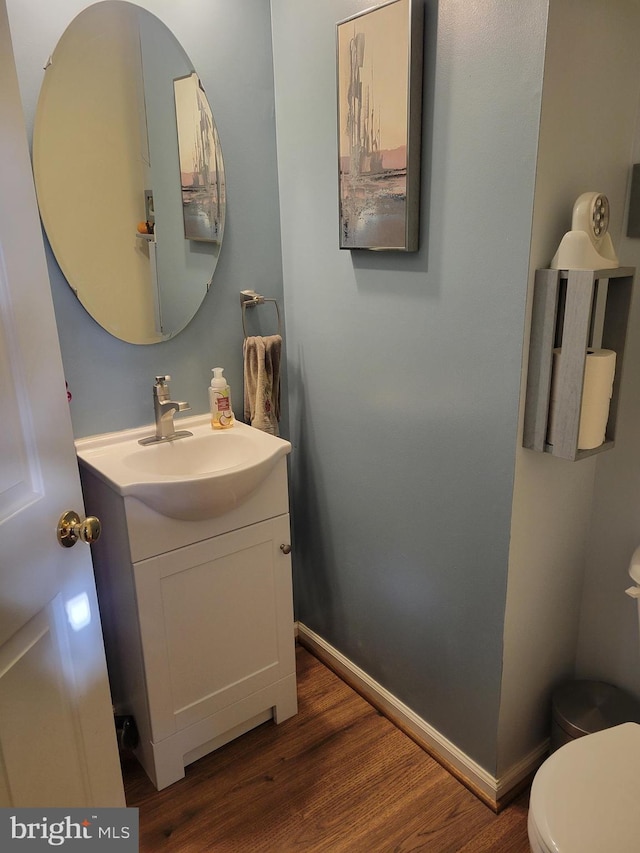 bathroom with toilet, vanity, and hardwood / wood-style flooring