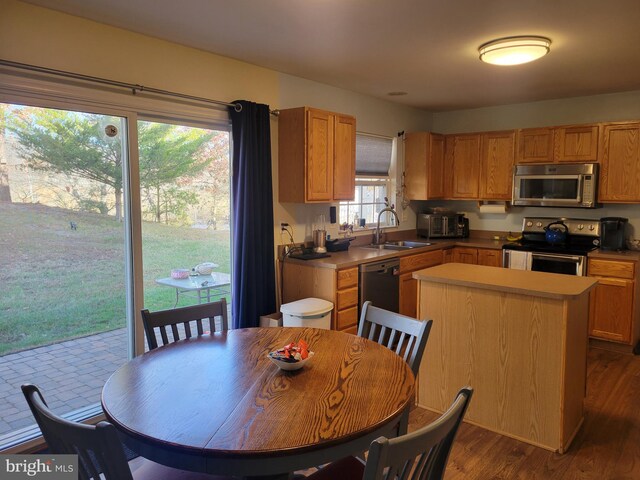 kitchen featuring sink, a center island, dark wood-type flooring, and appliances with stainless steel finishes