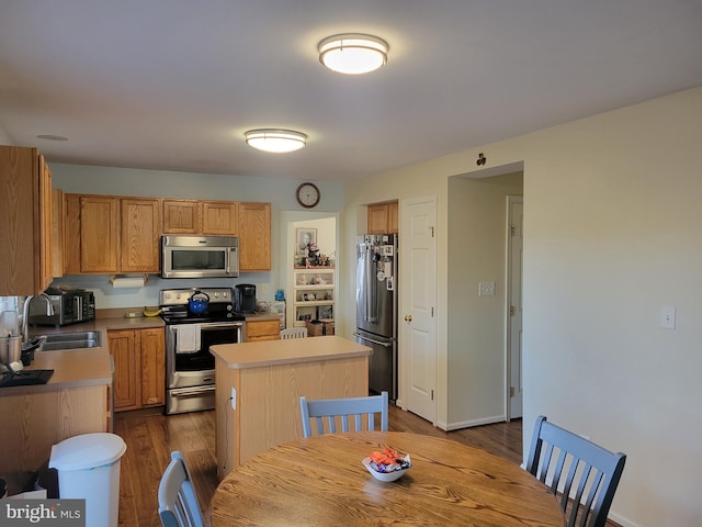 kitchen featuring dark hardwood / wood-style floors, a center island, sink, and appliances with stainless steel finishes