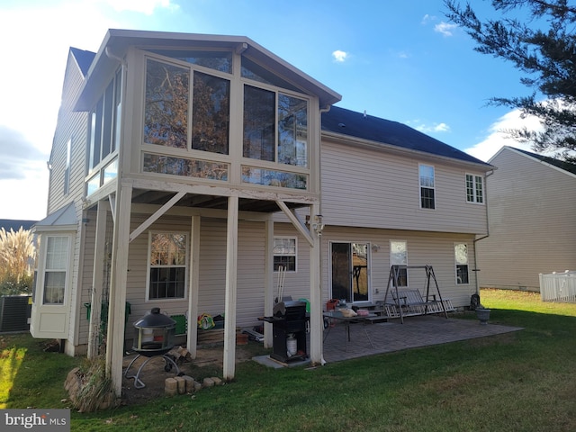 back of house featuring a sunroom, cooling unit, a patio area, and a lawn