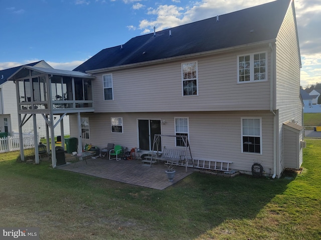 back of property featuring a lawn, a sunroom, and a patio