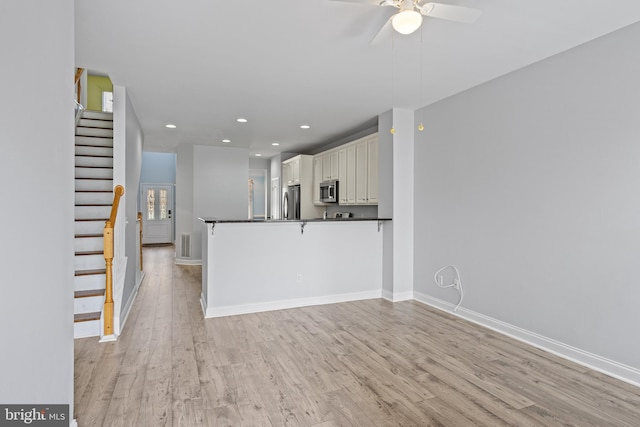 kitchen featuring kitchen peninsula, ceiling fan, light hardwood / wood-style floors, and appliances with stainless steel finishes