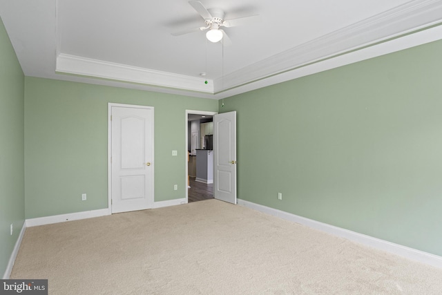 unfurnished bedroom featuring a tray ceiling, ceiling fan, and carpet floors