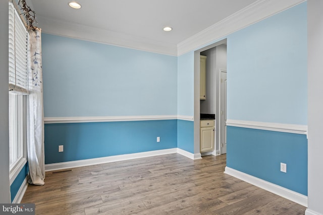 spare room featuring wood-type flooring and ornamental molding