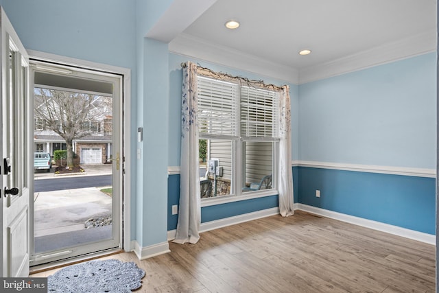 foyer featuring ornamental molding, light hardwood / wood-style flooring, and a healthy amount of sunlight