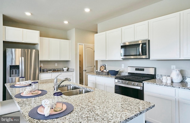 kitchen with white cabinets, a kitchen island with sink, sink, and appliances with stainless steel finishes