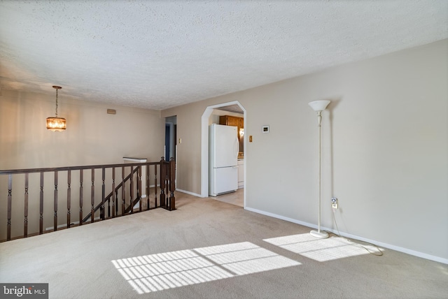 spare room with light carpet, a textured ceiling, and a chandelier