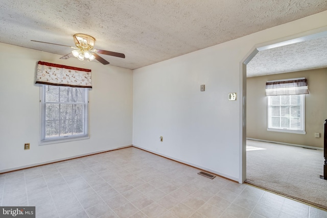 carpeted spare room featuring a textured ceiling and ceiling fan