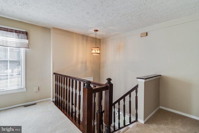 stairs with carpet flooring, a textured ceiling, and an inviting chandelier