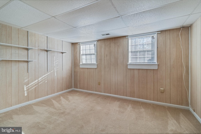 basement with wood walls, a drop ceiling, and carpet