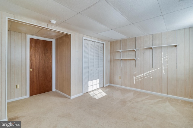 unfurnished bedroom featuring light carpet, a closet, and wood walls