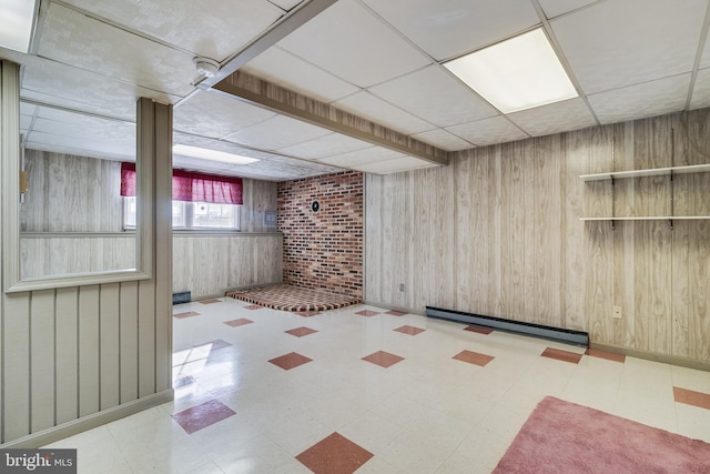 basement with a paneled ceiling and wooden walls