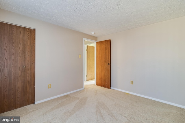 spare room with light colored carpet and a textured ceiling