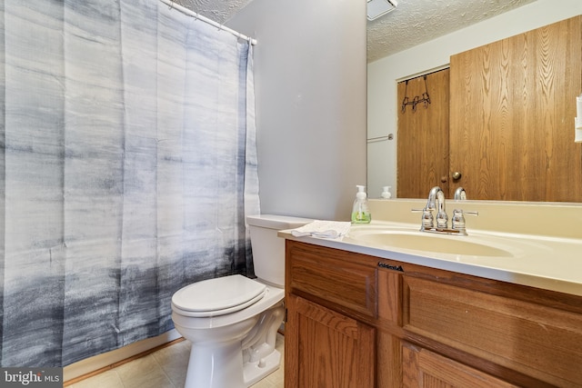 bathroom with tile patterned flooring, vanity, toilet, and a textured ceiling