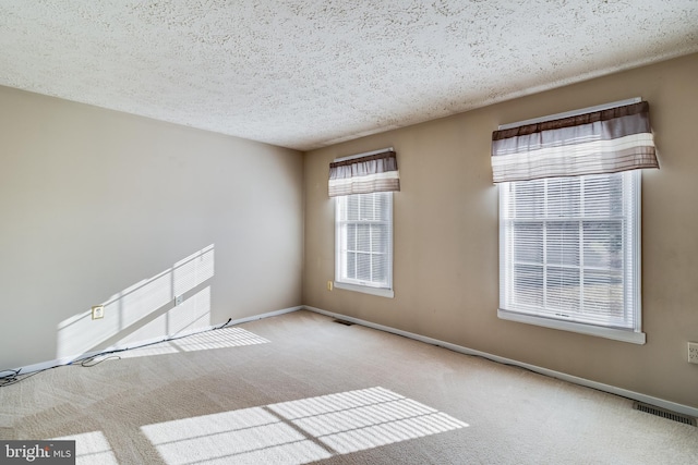 carpeted empty room featuring a textured ceiling