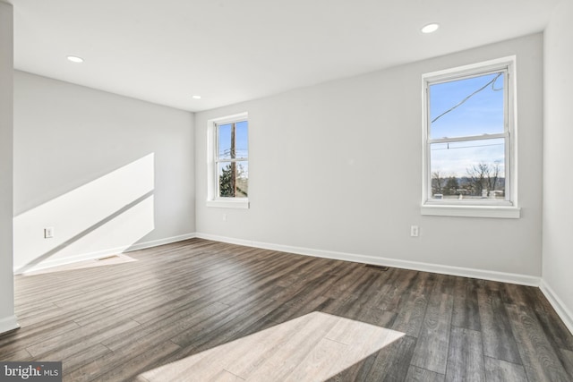 empty room with plenty of natural light and dark hardwood / wood-style flooring