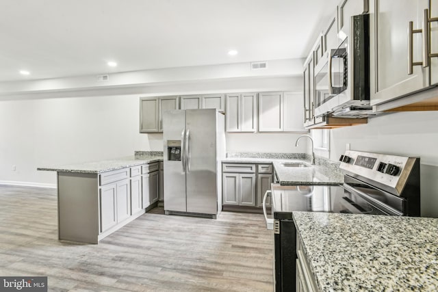 kitchen with gray cabinetry, light hardwood / wood-style floors, and appliances with stainless steel finishes