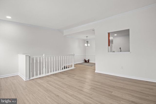 unfurnished room with ornamental molding, an inviting chandelier, baseboards, and wood finished floors