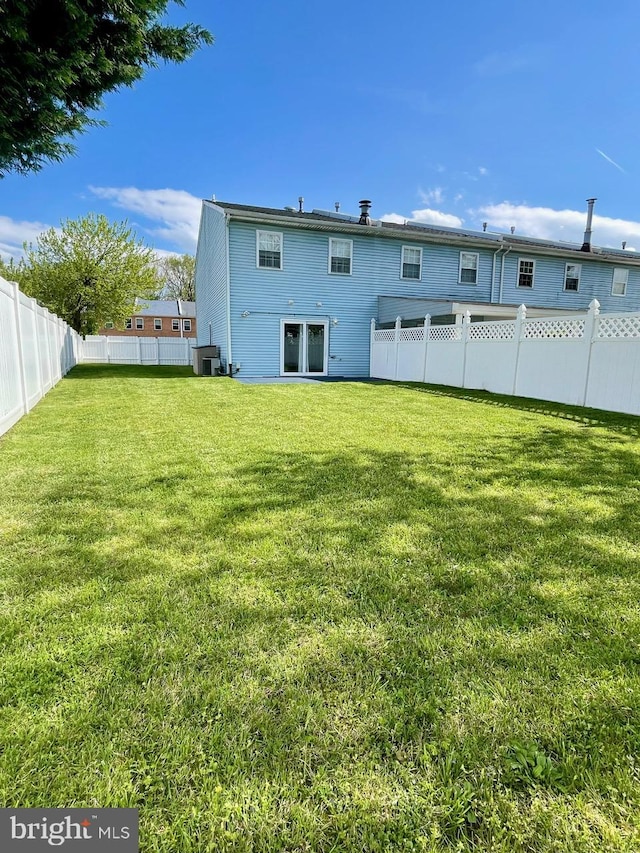 rear view of house featuring a fenced backyard and a lawn