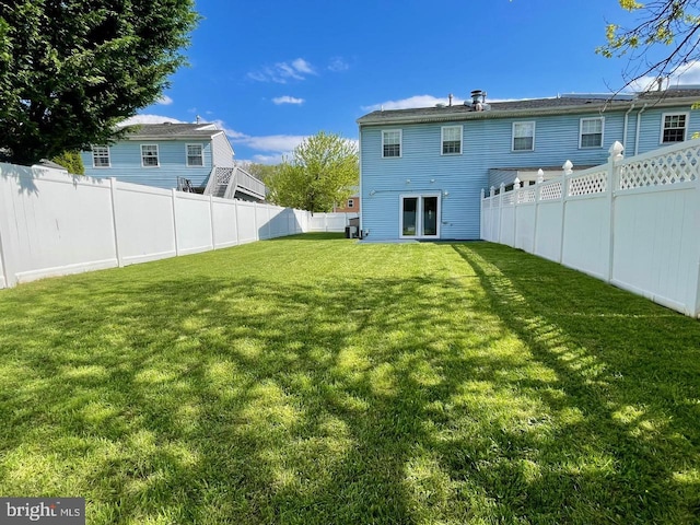 rear view of house featuring a fenced backyard and a yard