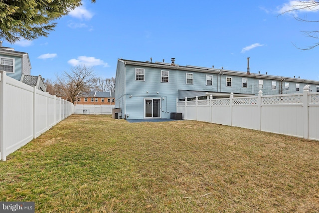 rear view of house with a fenced backyard, cooling unit, and a yard