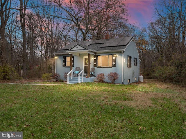 view of front facade with solar panels, a porch, and a lawn