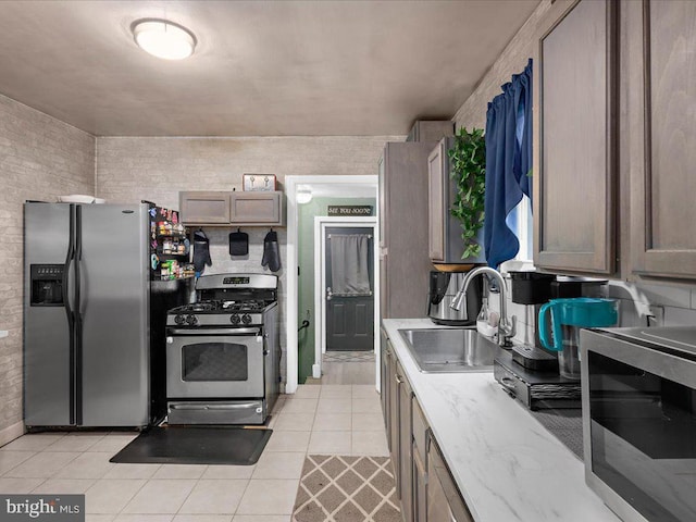 kitchen with light stone counters, sink, light tile patterned flooring, and stainless steel appliances