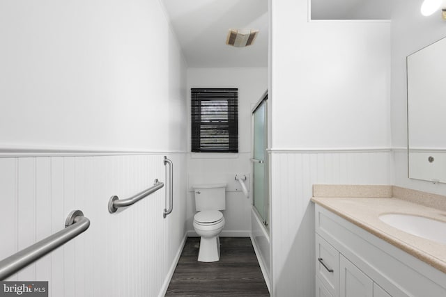 full bathroom with shower / bath combination with glass door, toilet, vanity, and hardwood / wood-style flooring