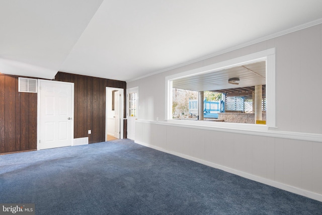 empty room with carpet floors, crown molding, and wooden walls