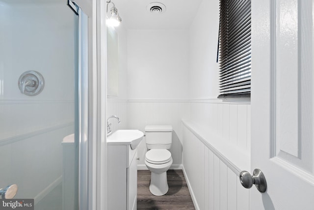 bathroom with hardwood / wood-style flooring, vanity, toilet, and a shower with shower door