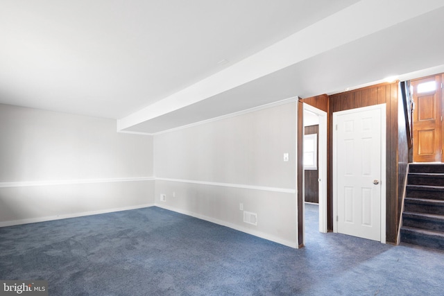 carpeted spare room with wooden walls