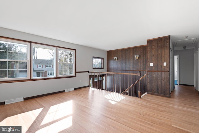 unfurnished room with wood walls, light hardwood / wood-style floors, and a wealth of natural light