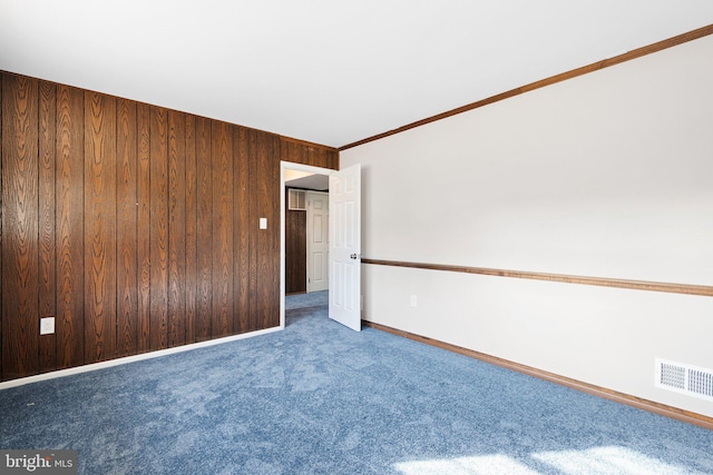 carpeted spare room with wooden walls