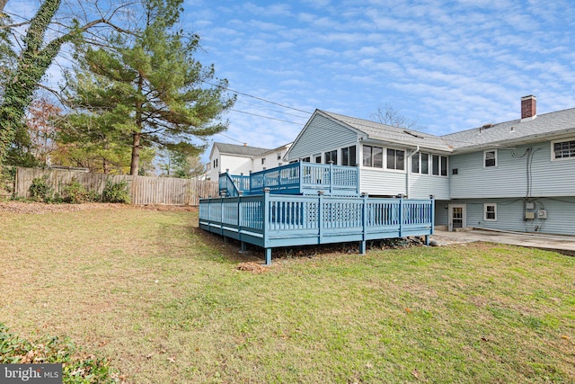 back of house with a sunroom, a deck, and a lawn