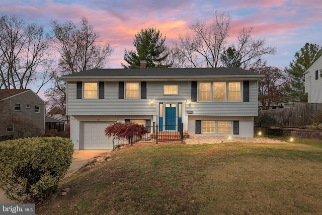 split foyer home featuring a garage and a lawn