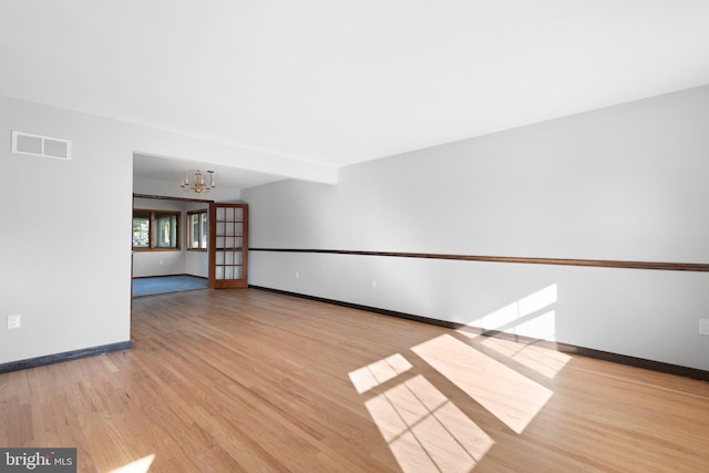 spare room with an inviting chandelier and light wood-type flooring