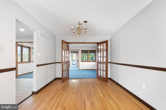 interior space featuring french doors, light hardwood / wood-style flooring, plenty of natural light, and a notable chandelier