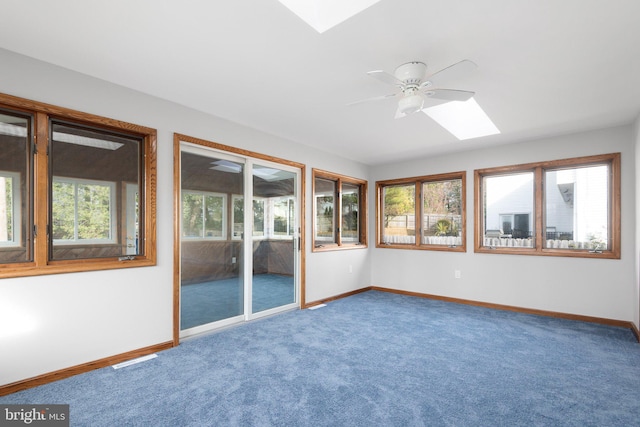 unfurnished sunroom featuring a skylight, a wealth of natural light, and ceiling fan