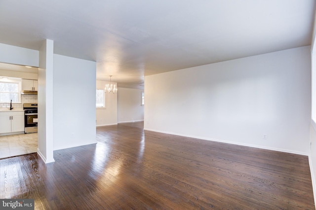 unfurnished living room with dark hardwood / wood-style flooring, plenty of natural light, and an inviting chandelier