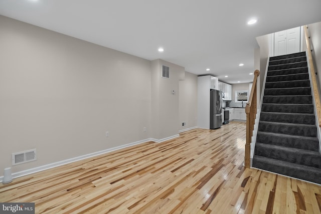 unfurnished living room featuring sink and light hardwood / wood-style floors