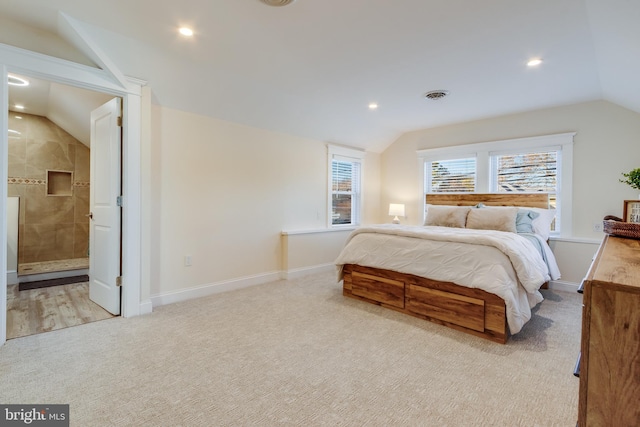 carpeted bedroom featuring ensuite bathroom and vaulted ceiling