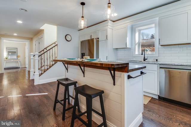 kitchen with sink, a breakfast bar, white cabinets, and appliances with stainless steel finishes