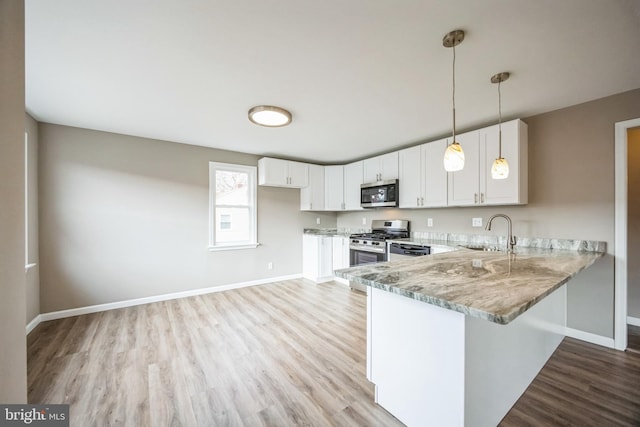 kitchen with light stone countertops, sink, hanging light fixtures, white cabinets, and appliances with stainless steel finishes