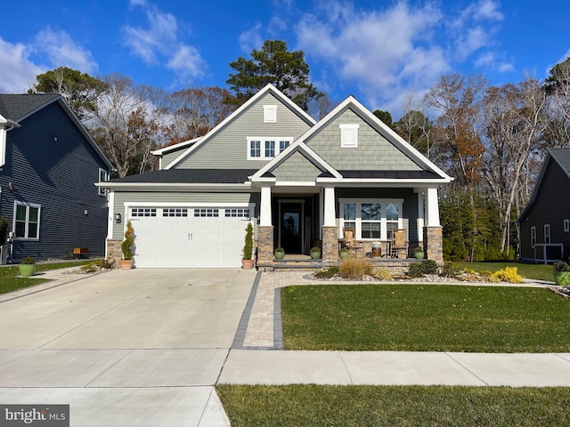 craftsman-style house featuring covered porch, a garage, and a front lawn