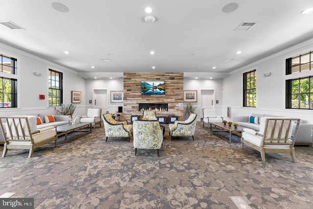 carpeted living room with a wealth of natural light, a large fireplace, and ornamental molding