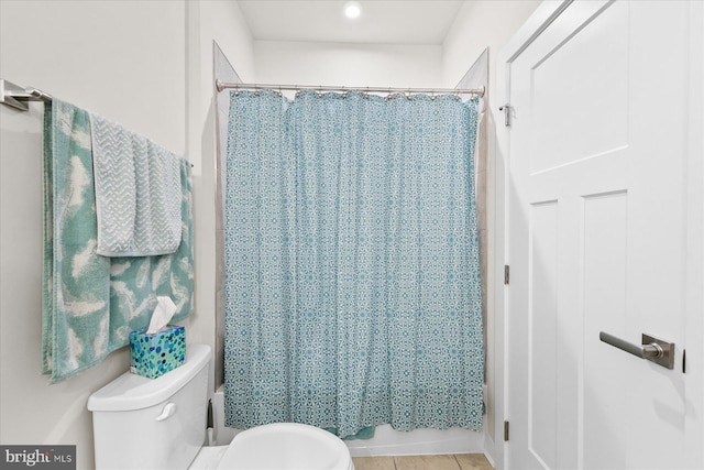 bathroom with tile patterned floors, shower / tub combo with curtain, and toilet