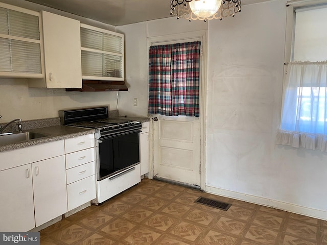 kitchen featuring white range with gas stovetop, dark parquet floors, white cabinets, and sink